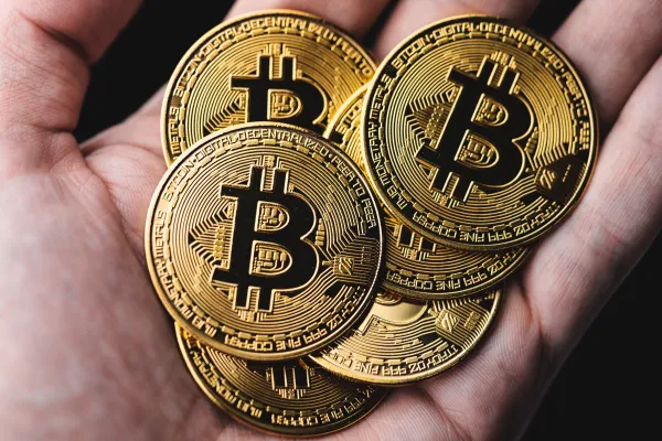 Gold coins with a Bitcoin logo held in a hand